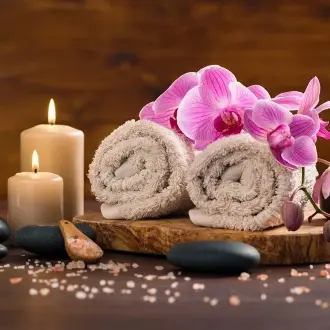 A wooden tray with rolled up towels and candles.