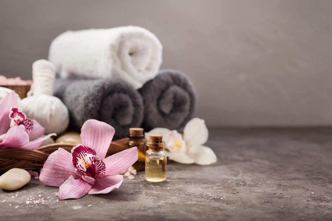 A close up of towels and flowers with an oil bottle